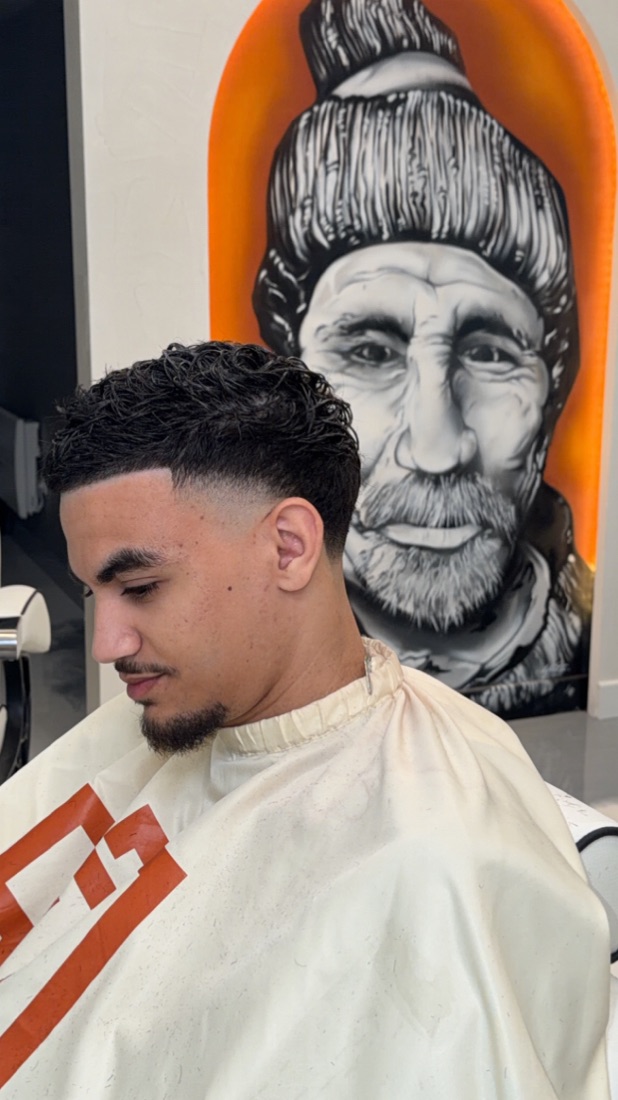Coupe dégradé bas avec cheveux bouclés et barbe taillée — Rijal Barber Club